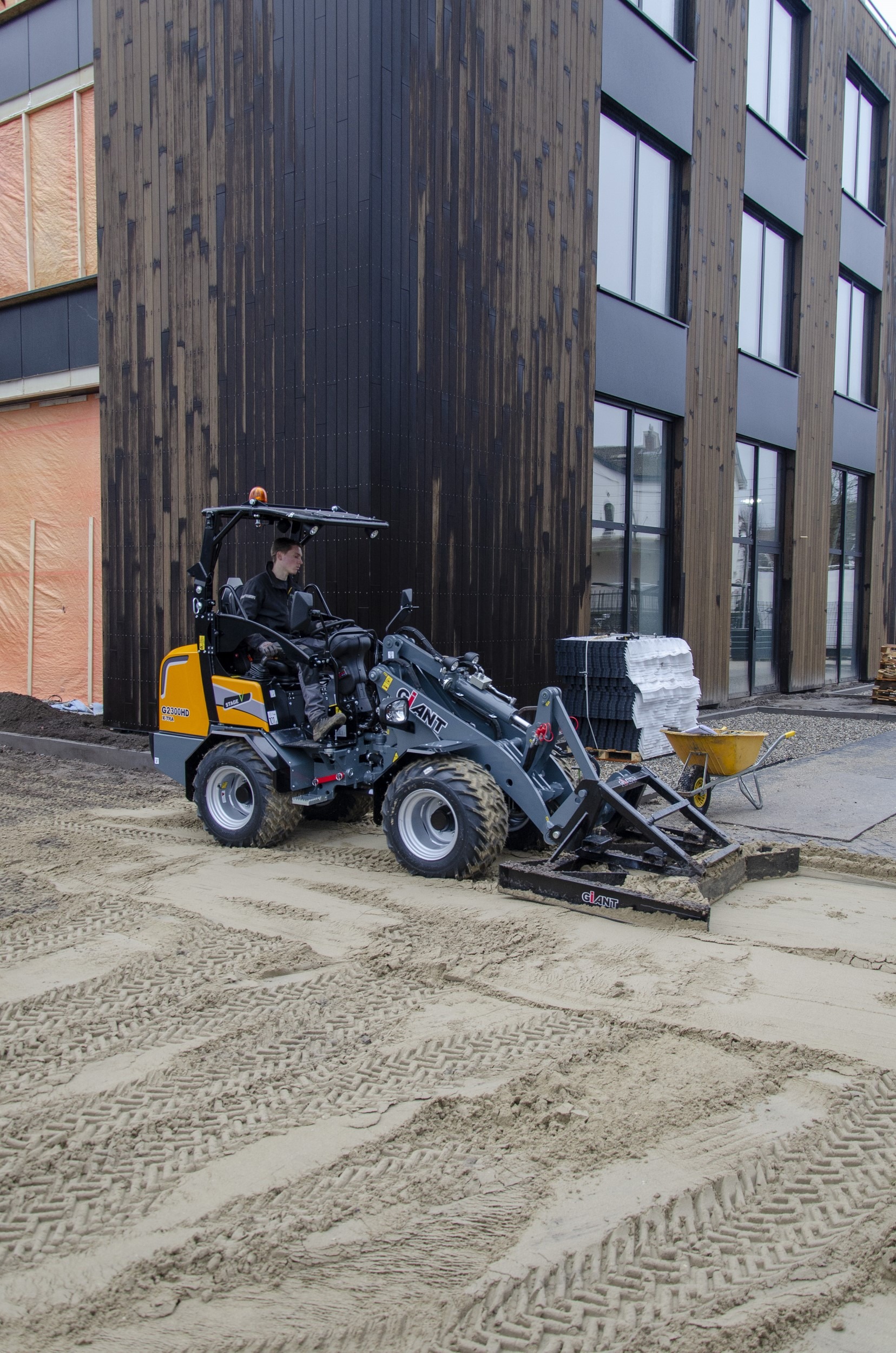 Aplatissement de terrain sur un chantier pour niveler le sol avec la Chargeuse G2300 X-TRA HD et son accessoire dédié
