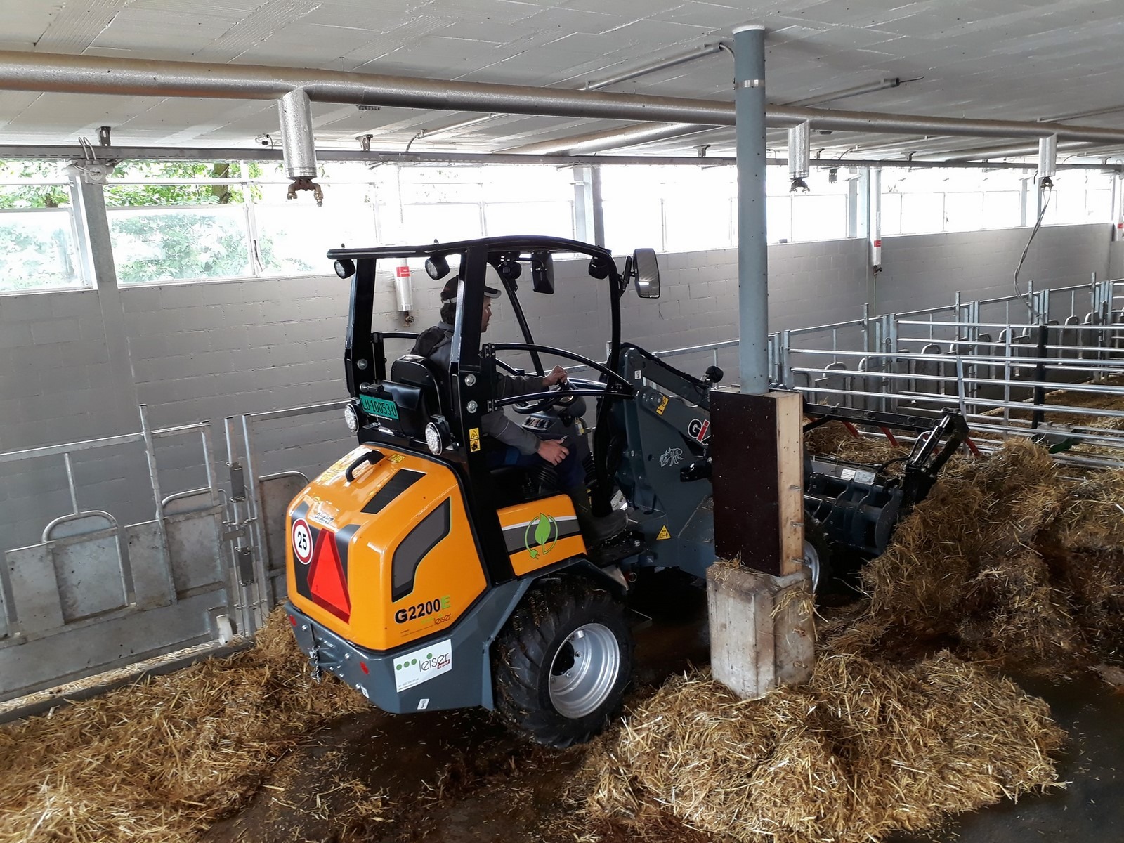 Nettoyage d'un enclos étroit à bétail dans une ferme grâce à la CHARGEUSE GIANT G2200E électrique.